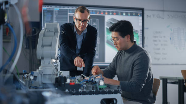 istock Chief Engineer Helping Asian Student of Engineering Faculty Work With Computer Motherboard and Processor. People Discussing with Each Other. Science, Robotics and Engineering Concept. 1448502267