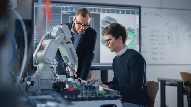 istock Product Supervisor Consults Young Engineer Working with Optimization of Robot Arm. People Doing Robotic Hand Maintenance Ideas. High-Tech Science and Engineering Concept. Medium Shot 1448502310