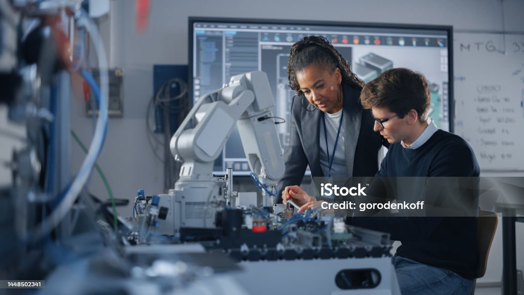 Male Student Engineer Discussing Ideas with Black Teacher while Working with Computer Processor. Man Uses Screwdriver. High-Tech Science and Engineering Concept. Medium Shot Engineer Stock Photo