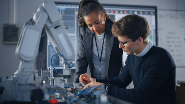 istock Black Teacher Giving Advices to her Student, Uses Screwdriver During the Lesson. Engineer Working with Motherboard and Processor. High-Tech Science and Engineering Concept 1448502366