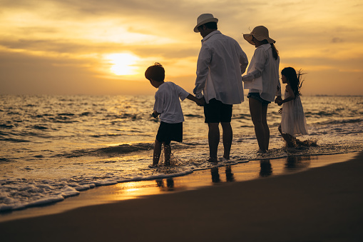 Silhouette of happy family at sunset on beach travel, Parents playing with child on beach, Family on beach holiday vacation, Freedom and travel concept