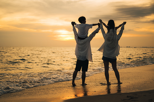 Silhouette of family with beach therapy, Happy family spending time together at beach, Parents give children piggyback on the beach, Travel on beach with sunset view, Family with holiday and travel concept