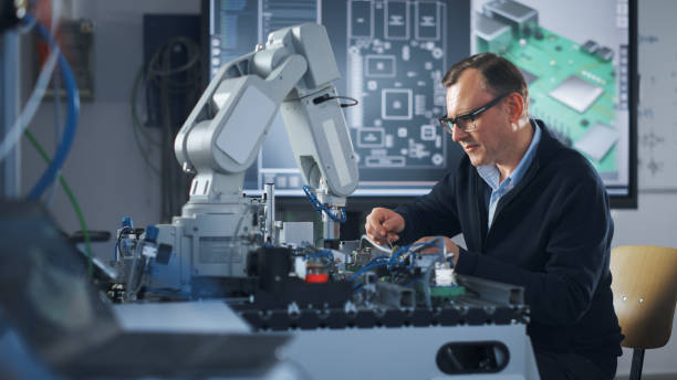 retrato de engenheiro sorridente usando chave de fenda enquanto trabalha com microchip de braço robótico. homem olhando para a câmera durante seu experimento com mão biônica. conceito de ciência e engenharia de alta tecnologia - technology personal accessory hightech business - fotografias e filmes do acervo