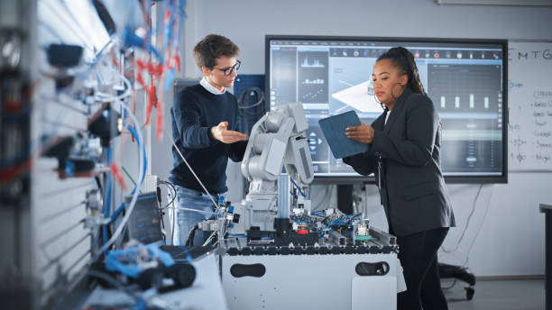 istock Black Teacher Holding Tablet and Discussing Robot Hand with Caucasian Student During the Lesson at School. Computer Science Education, Design, Learning Concept. Slow Motion. 1448503743