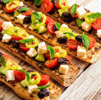 Homemade aprese bruschetta toasts with cherry tomatoes, mozzarella and basil on table.