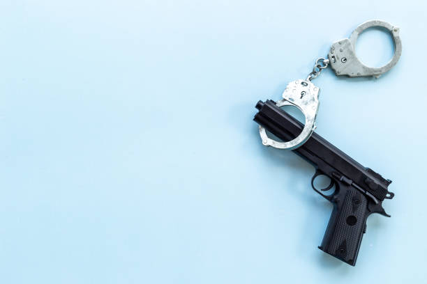 istock Crime concept. Hand gun weapon with handcuffs 1448505653