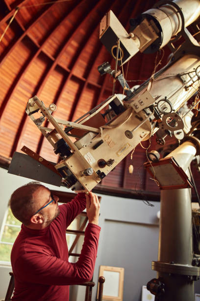 istock Astronomer with a big astronomical telescope in observatory doing science research. 1448506310