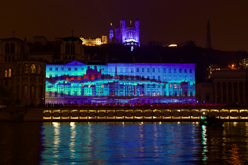 Fantastic images projected on a building on the quay of saone with the basilica Notre Dame de Fourviere in the background for the Festival of lights 2022. It represents the Fourvière Hill.