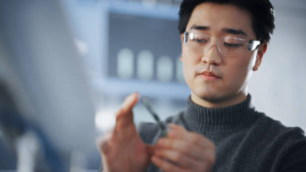 istock Asian Student Examining Micro Chip and Takes Out Memory Card While Working on Complicated Project in The Laboratory of Modern University. Futuristic Technologies, Science and Development Concept. 1448507331