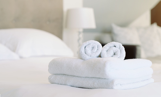 Empty room, hospitality and clean towels on a bed at a condo, resort or motel. Hotel, attention to detail and preparation for customers at a spa with luxury soft fabric, linen and cotton cloth.