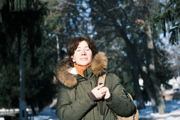 istock Mature woman is catching sunlight on her face while walking in winter public park 1448507745