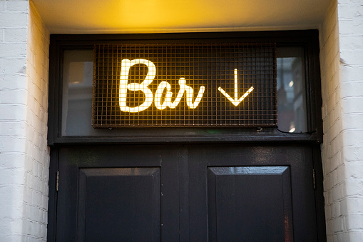 Illuminated sign above an entrance to a bar in Central London