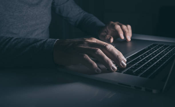 istock Hands typing on laptop keyboard. Man working on computer. Dark mood. Technology, business concept 1448512415