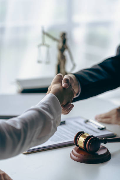 Lawyer shaking hands with client after agreement Gavel Justice hammer on wooden table with judge and client shaking hands after advice in courtroom, notary service concept stock photo