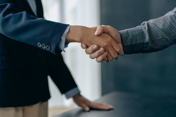 Businessmen shaking hands with clients in modern conference room The team leader meets the group to greet each other. Handshake showing trust and respect, financial concept  
 vertical image stock photo
