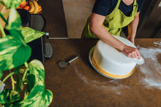 istock Unrecognisable woman in bakery decorating wedding cake with white fondant. DIY, sequence, step by step, multiple image. 1448513527