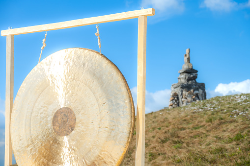 Bronze gong hanging against blue sky.