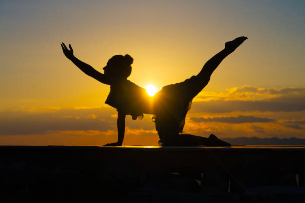 Silhouette of woman practising yoga on deck during sunset.