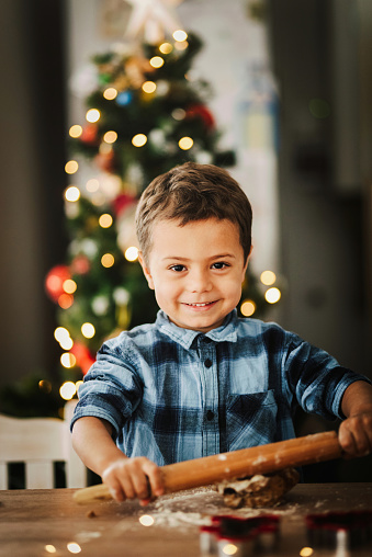 Child making Christmas gingerbread cookies. Child playing with dough close up photo.