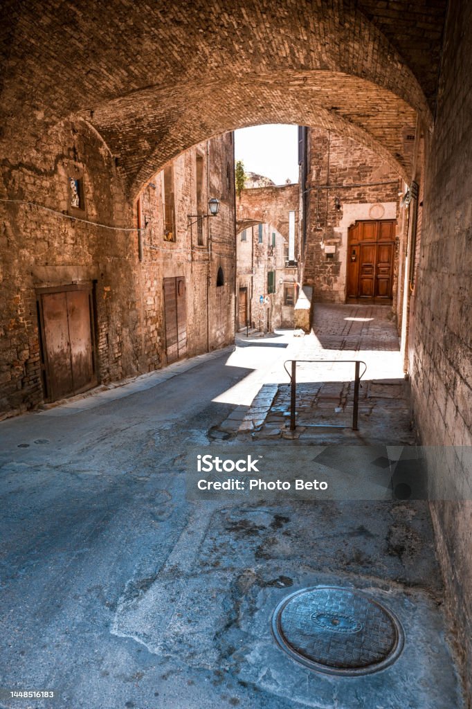 A beautiful stone arched alleyway in the medieval heart of Perugia in Umbria in central Italy A characteristic and suggestive stone arched alley in the Rione di Porta Santa Susanna (St Susanna gate district) in the medieval heart of Perugia, in Umbria, central Italy. Founded by the Etruscans on an ancient Umbrian settlement, Perugia is one of the most loved and visited medieval Italian cities, rich in artistic and architectural treasures that span almost three thousand years of history. The Umbria region, considered the green lung of Italy for its wooded mountains, is characterized by a perfect integration between nature and the presence of man, in a context of environmental sustainability and healthy life. In addition to its immense artistic and historical heritage, Umbria is famous for its food and wine production and for the high quality of the olive oil produced in these lands. Super wide angle image in high definition format. Alley Stock Photo