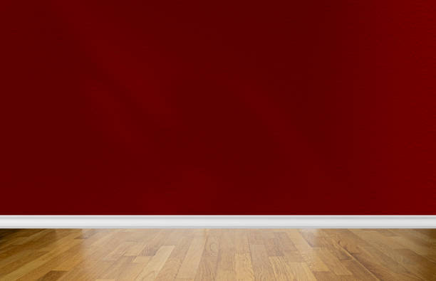 istock Interior of a room with blank red wall, abstract shadows and pine parquet floor. Space for text 1448521252