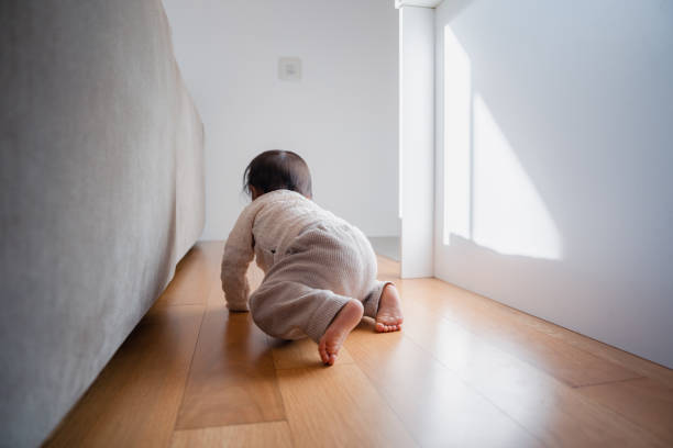Father watching over son crawling on the floor.