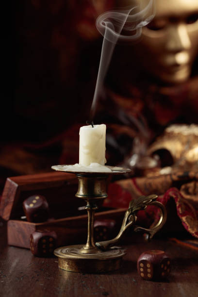 istock Extinguished candle, dice, and carnival masks on an old wooden table. 1448527675