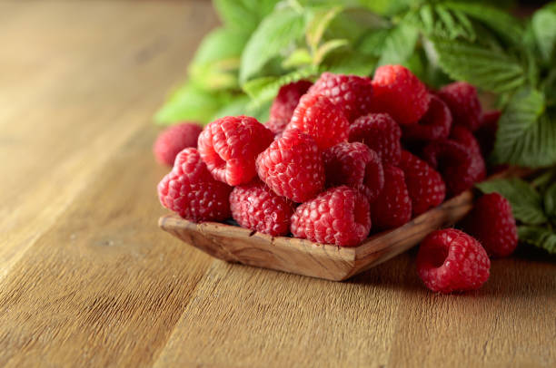 istock Ripe juicy raspberries with leaves. 1448527686