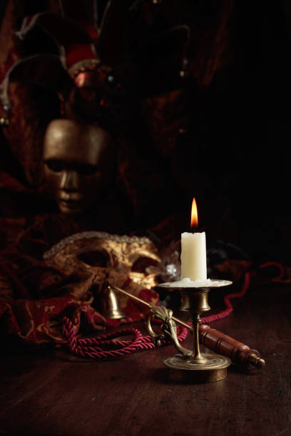 istock Burning candle in an old brass candlestick and carnival masks. 1448527718