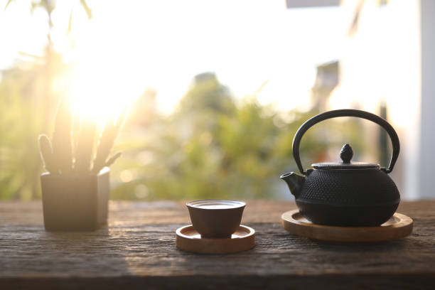 屋外の木製テーブルの上に金属製の黒いやかんティーポットと小さなティーカップと植木鉢 - japanese tea cup ストックフォトと画像
