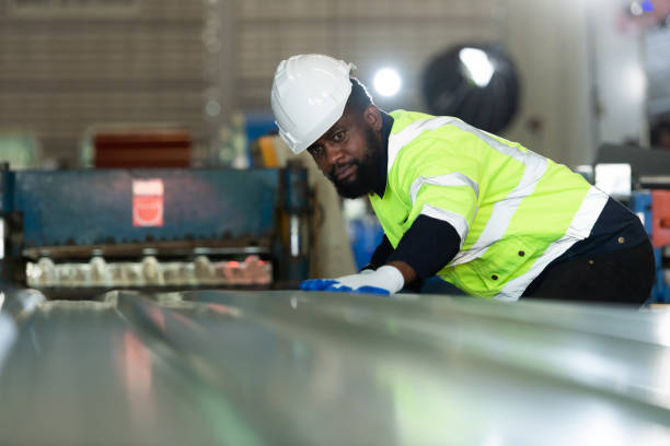 Young engineers engineers testing and confirming that the machinery at the factory Young engineers engineers testing and confirming that the machinery at the factory that creates metal sheet tiles is functioning as intended sheet-metal stock pictures, royalty-free photos & images