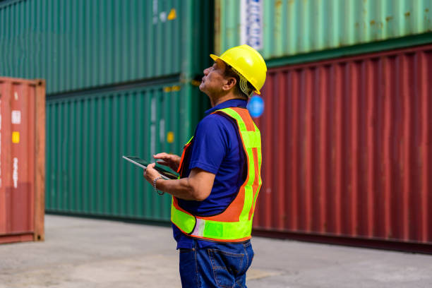 istock Logistics worker in yellow helmet checking and operating at containers terminal 1448529630