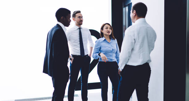 istock Multiethnic office workers standing near lift and talking at office 1448530243