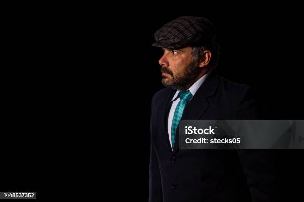 Businessman Looking Aside Wearing A Suit And A Flat Cap Stock Photo - Download Image Now
