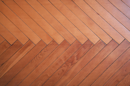 Herringbone pattern of old wooden parquet floor closeup. Fragment of wood vintage flooring.