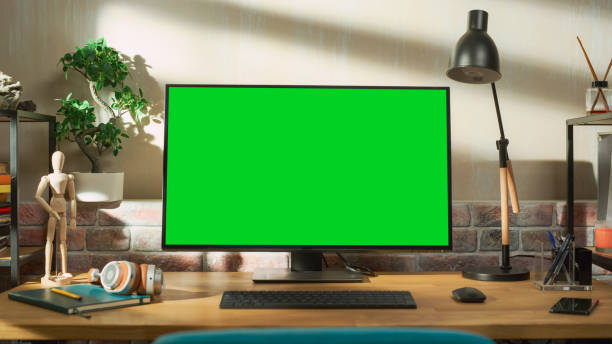 Desktop Computer Monitor Standing on a Table with a Green Screen Chromakey Mock Up Display. Cozy Empty Loft Apartment with a Lamp, Notebooks and Smartphone on the Table. Arc Shot. Desktop Computer Monitor Standing on a Table with a Green Screen Chromakey Mock Up Display. Cozy Empty Loft Apartment with a Lamp, Notebooks and Smartphone on the Table. Arc Shot. fx stock pictures, royalty-free photos & images