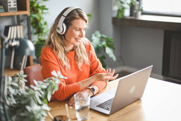 mature adult woman with laptop and  headphones ( video call) stock photo
