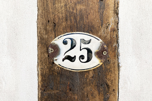 house number twenty-five - old rusty 25 plaque mounted on timber frame building