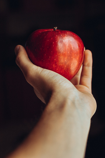 A man hand offering a red apple