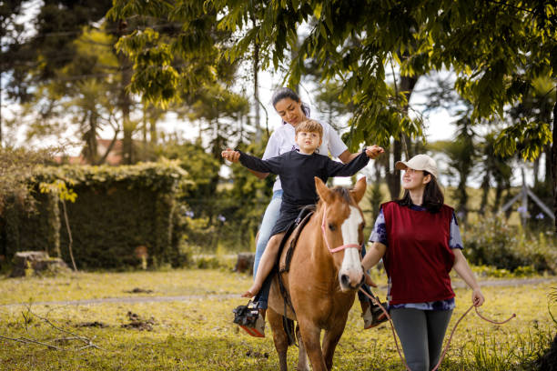Little boy riding a horse with therapists support