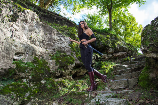 Beautiful warrior girl with sword hidden among rocks - warrior woman concept
