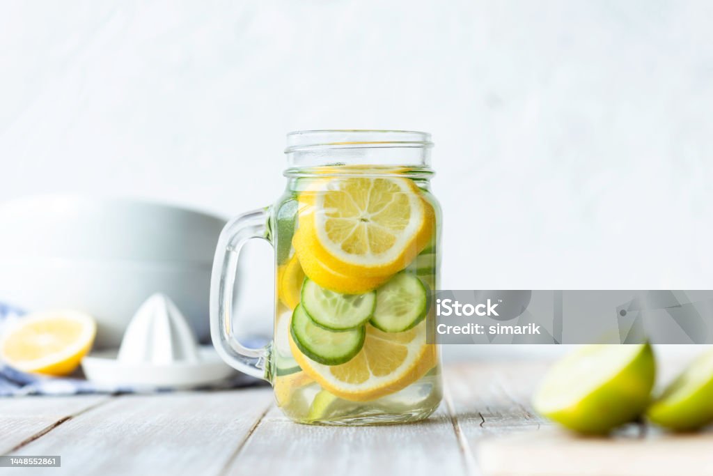 Detox Bottle of infused water on white wood with lemon and  cucumber slices. Antioxidant Stock Photo