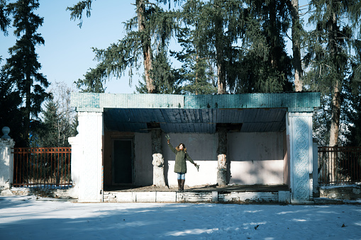 Mature woman is dancing on the old abandoned stage in winter park
