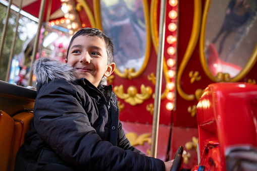 Cheerful little boy having fun on the Christmas carousel.
