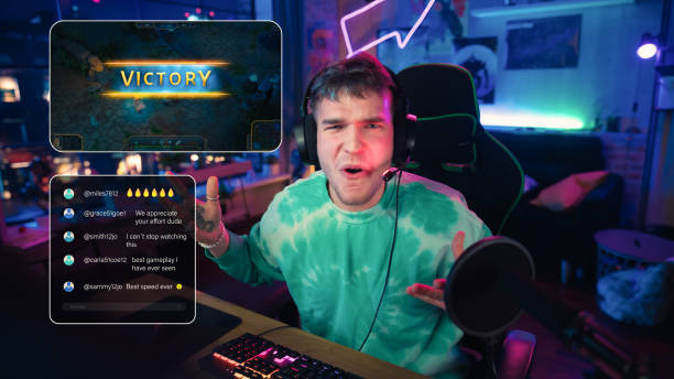 istock Hyped Streamer Playing a Video Game Online. Stylish Man Streaming His Gaming Progress from Home in Living Room Apartment. Followers Engaging Through Interface During Live Broadcast on Internet. 1448556425