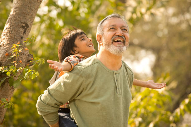 istock Bearded senior man piggybacking grandson in park during weekend 1448556528