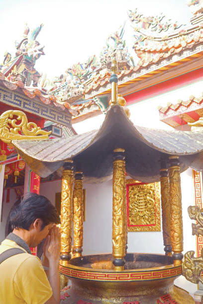 istock Visitor Paying Respect after Placing Incense Sticks in the Burner at Chinese Buddhist Temple 1448558581