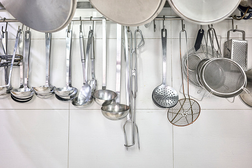 Kitchen Ladles, Cooking Skimmers and others Cookware hanging on the wall of a professional kitchen.