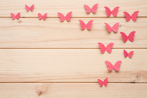 Some pink paper butterflies on a wooden surface. Springtime concept.