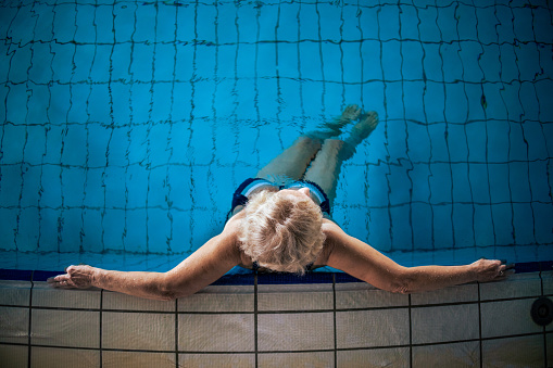 High angle view of unrecognizable senior Caucasian woman, relaxing in the swimming pool, at the spa center